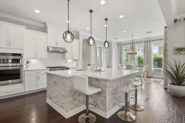 a kitchen with stainless steel appliances granite countertop a stove a sink dishwasher a refrigerator cabinets and wooden floor