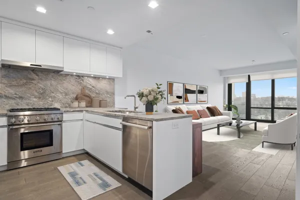 a kitchen with a sink dishwasher stove and white cabinets with wooden floor