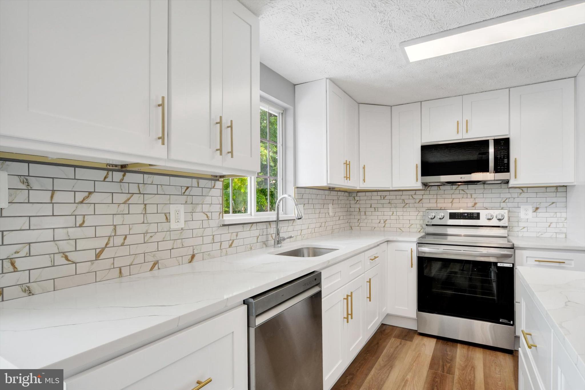 220 Sandhill Road Baltimore, MD 21221 - Photo 6 of 30 a kitchen with stainless steel appliances white cabinets a sink and a stove