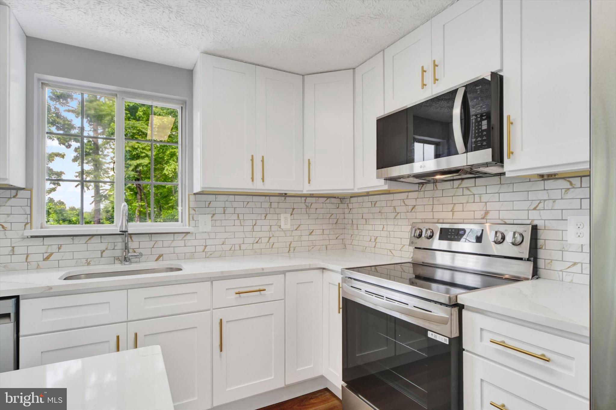 220 Sandhill Road Baltimore, MD 21221 - Photo 7 of 30 a kitchen with stainless steel appliances white cabinets and a stove top oven