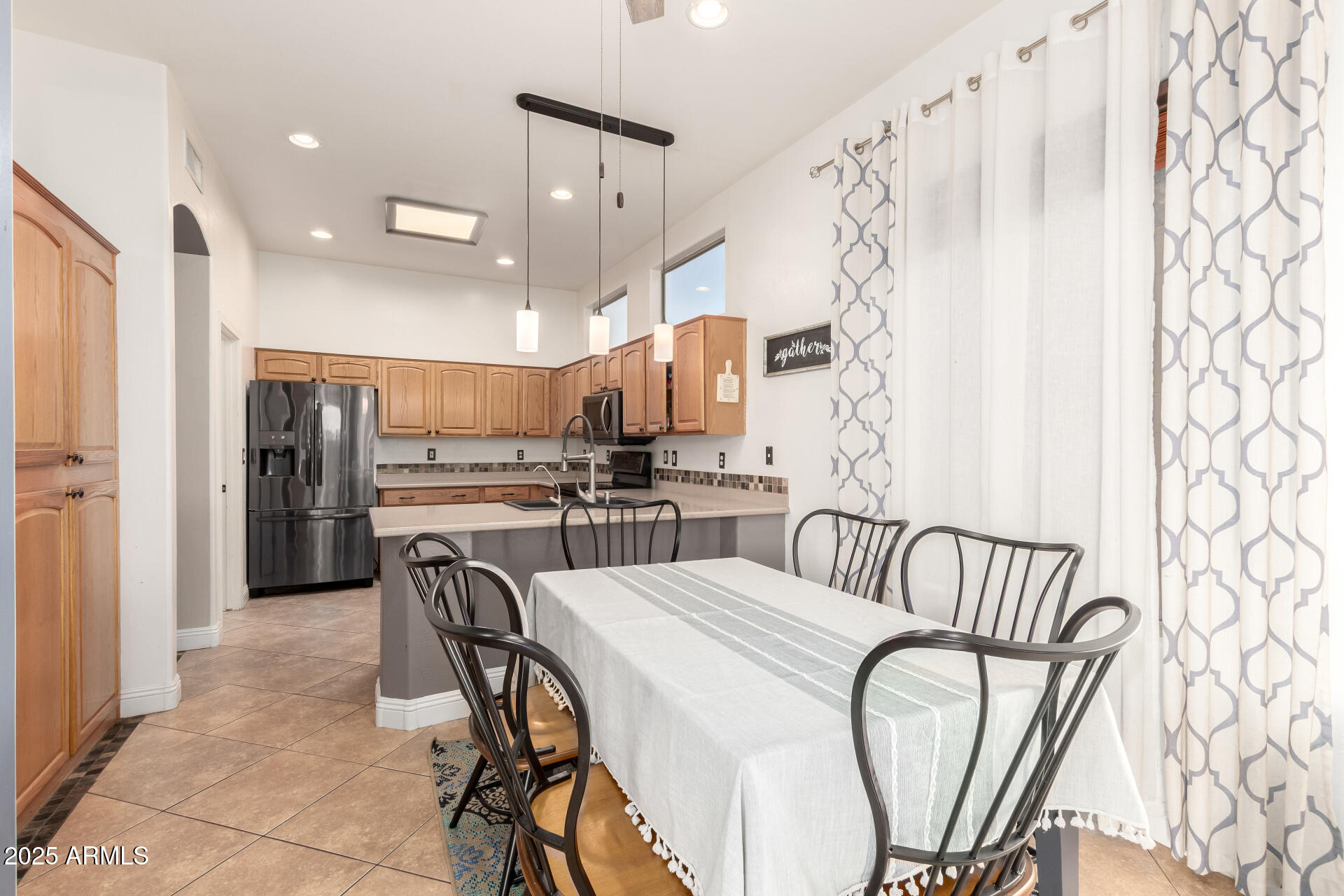 17441 West Arroyo Way Goodyear, AZ 85338 - Photo 9 of 27 a kitchen with stainless steel appliances a refrigerator a sink dishwasher a dining table and chairs with wooden floor