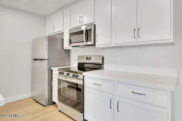 a kitchen with white cabinets and stainless steel appliances