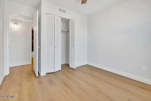 a view of an empty room with closet and a window