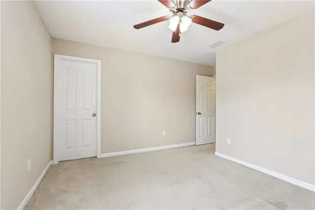 an empty room with a chandelier fan and windows