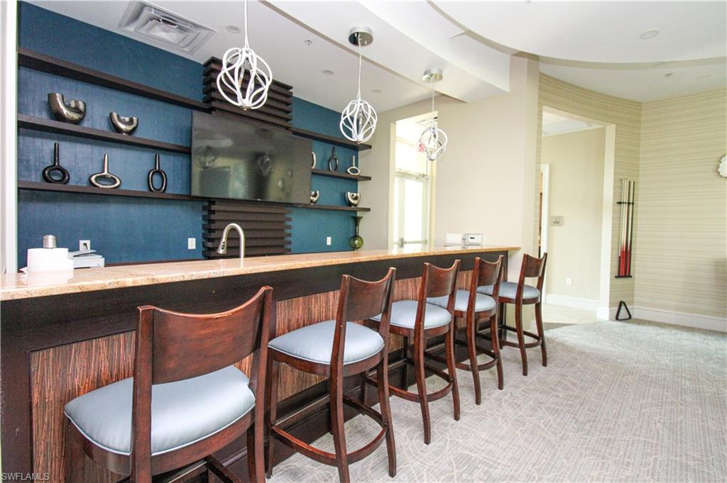 9123 Strada Place, Unit 7410 Naples, FL 34108 - Photo 19 of 50 Bar featuring carpet flooring, sink, and hanging light fixtures