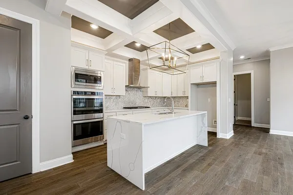 a large white kitchen with granite countertop a stove top oven a sink dishwasher and a fireplace with wooden floor