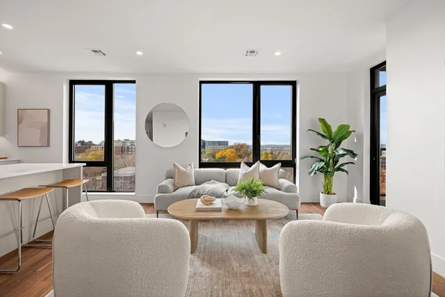 a living room with furniture potted plant and large windows