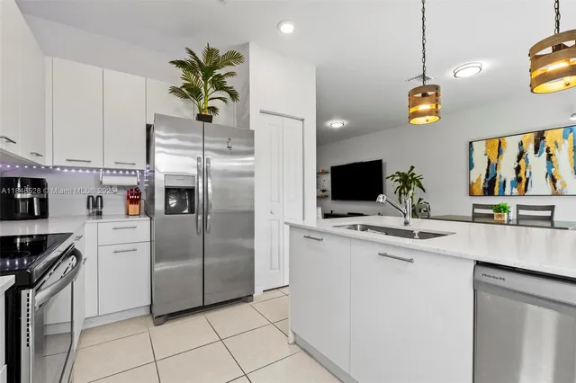 a kitchen with stainless steel appliances granite countertop a refrigerator a stove and a sink