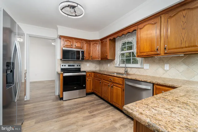 a kitchen with granite countertop a stove a sink and a refrigerator