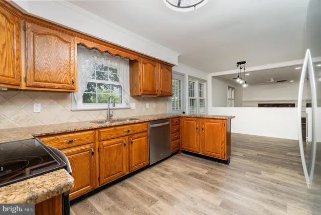 a large kitchen with stainless steel appliances granite countertop a stove a sink dishwasher and cabinets with wooden floor