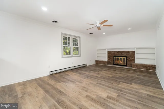 an empty room with fireplace and a ceiling fan