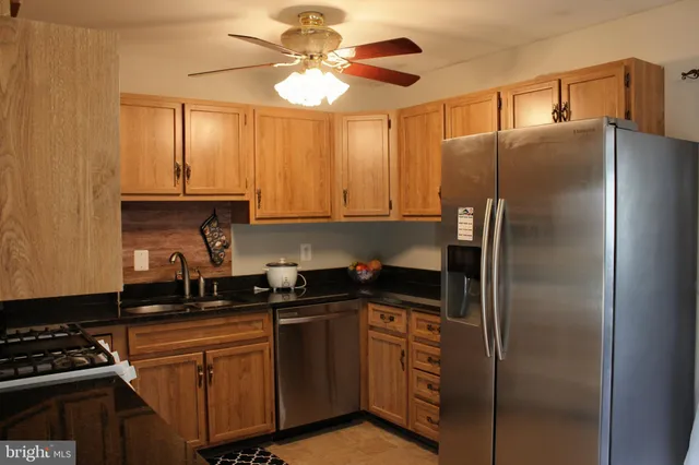 a kitchen with stainless steel appliances granite countertop a refrigerator a sink a stove with cabinets