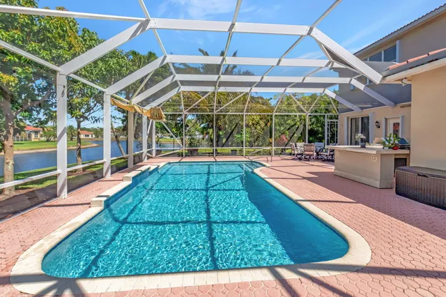 a view of a swimming pool with a lawn chairs under palm trees