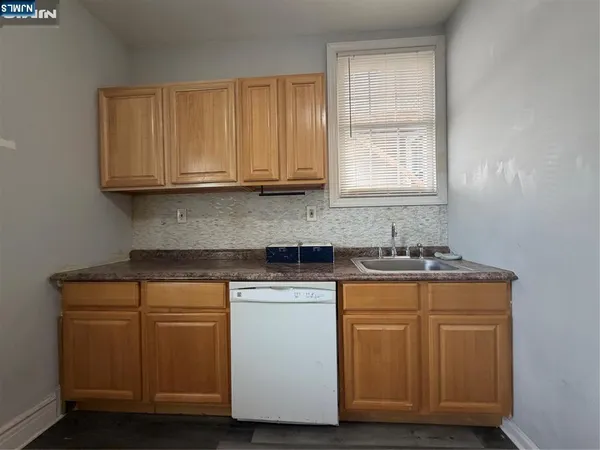 a kitchen with granite countertop wooden cabinets appliances a sink and a window