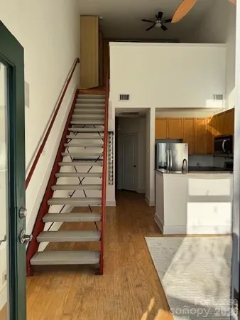 a view of an empty room with wooden floor and a bathroom