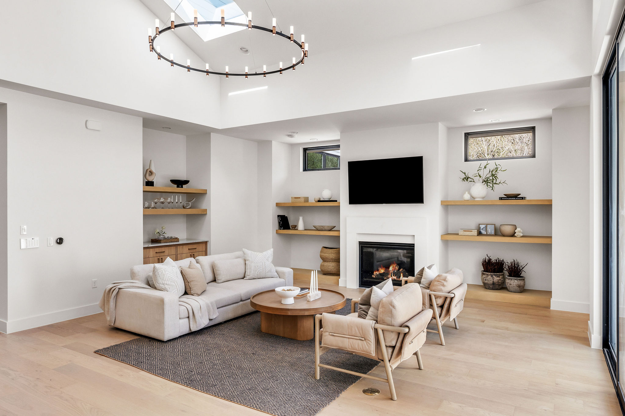 8307 Silver Ridge Drive Austin, TX 78759 - Photo 4 of 27 Living area featuring a high ceiling, light wood finished floors, a glass covered fireplace, and suspended lighting