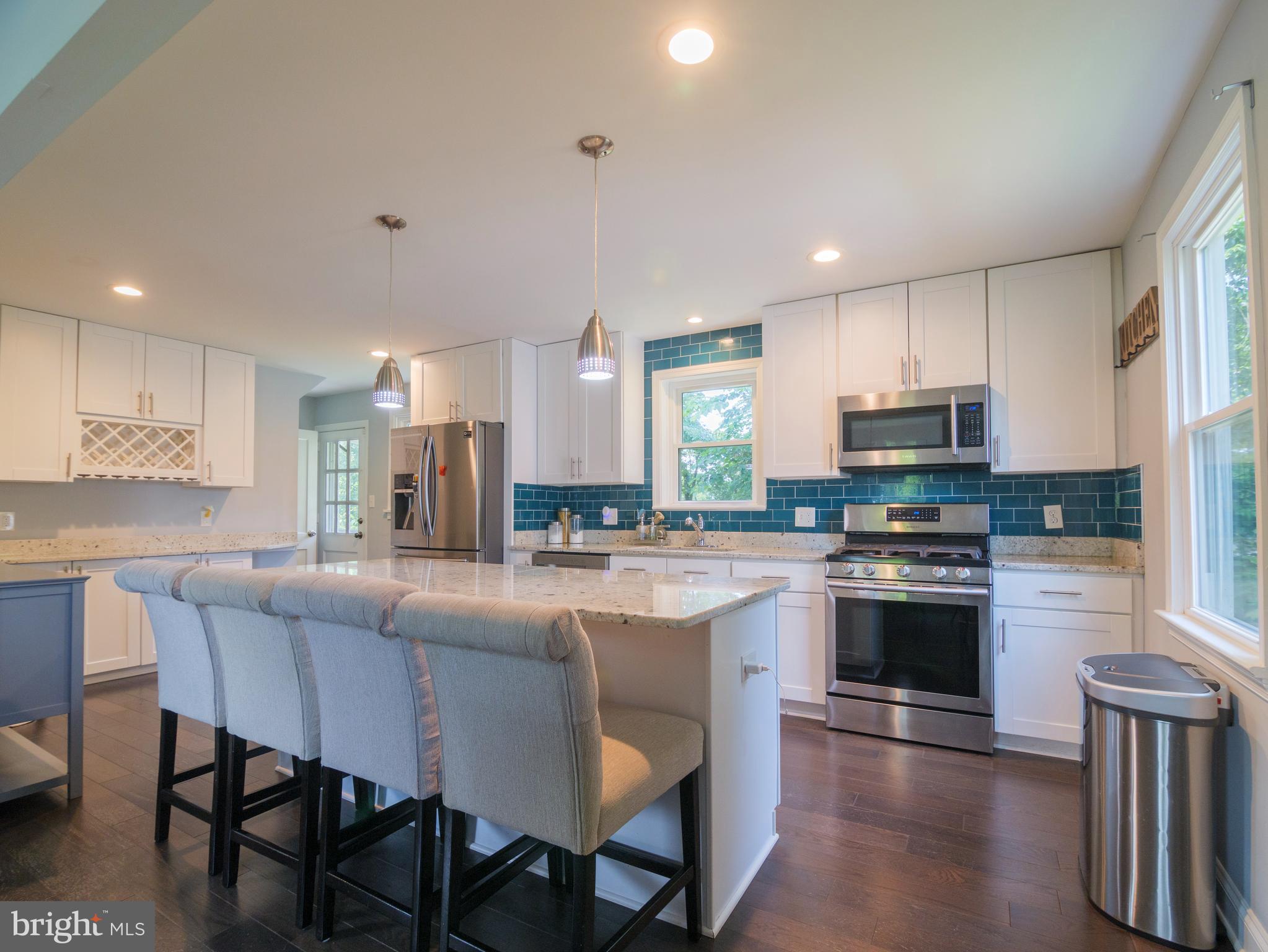 a kitchen with stainless steel appliances granite countertop a stove a sink a refrigerator a dining table and chairs