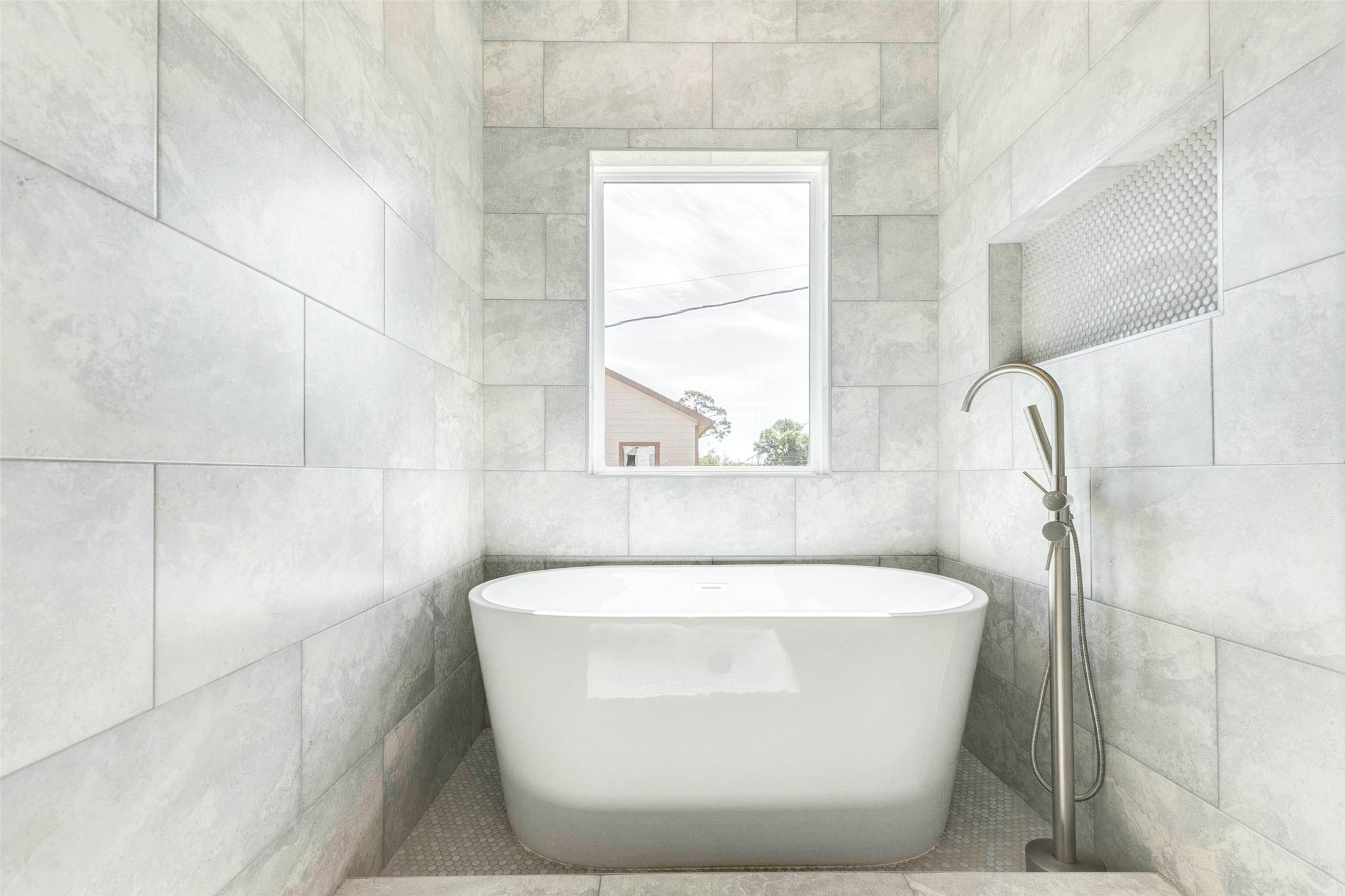 7115 England Street, Unit C Houston, TX 77021 - Photo 8 of 19 A freestanding soaking tub is centered beneath a large privacy window within a fully tiled wet area.