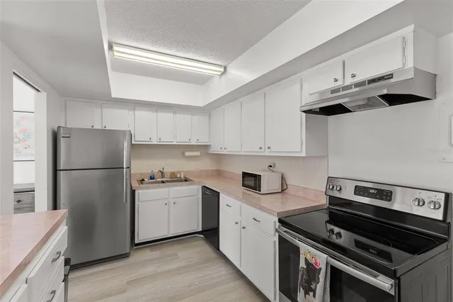 a kitchen with stainless steel appliances granite countertop white cabinets a refrigerator and a sink