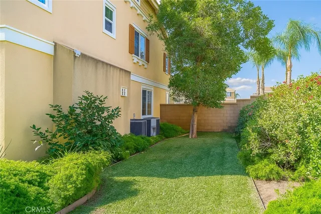 a backyard of a house with plants and palm tree