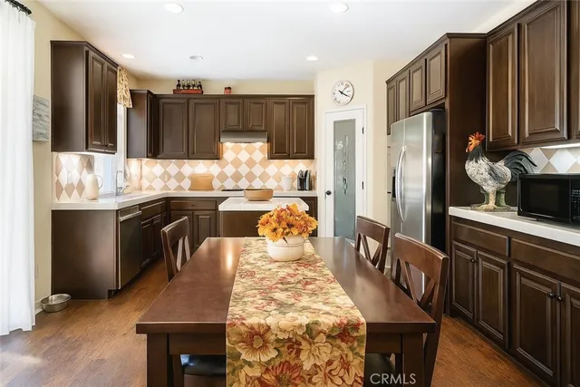 a kitchen with stainless steel appliances granite countertop a dining table chairs sink refrigerator and microwave