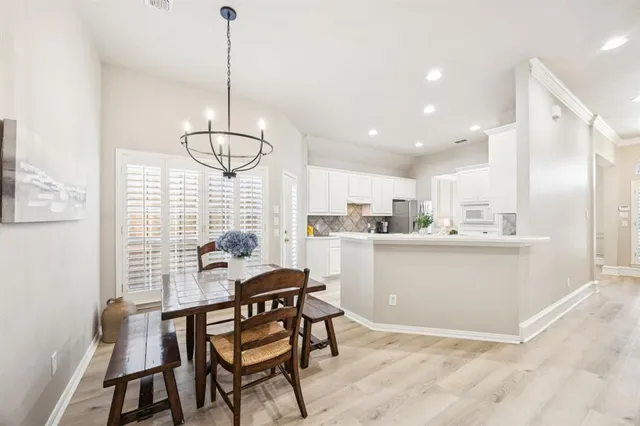 a kitchen with stainless steel appliances kitchen island granite countertop a dining table chairs and white cabinet