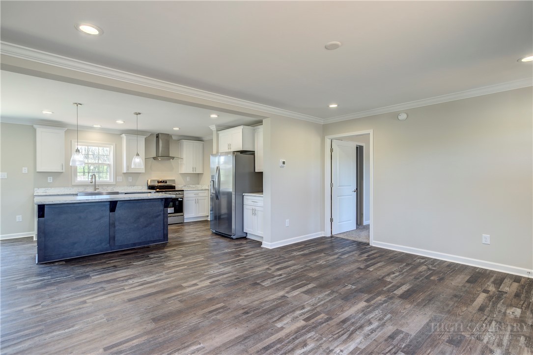 1052 Halsey Knob Road Sparta, NC 28675 - Photo 13 of 28 a large kitchen with a center island wooden floor stainless steel appliances and windows