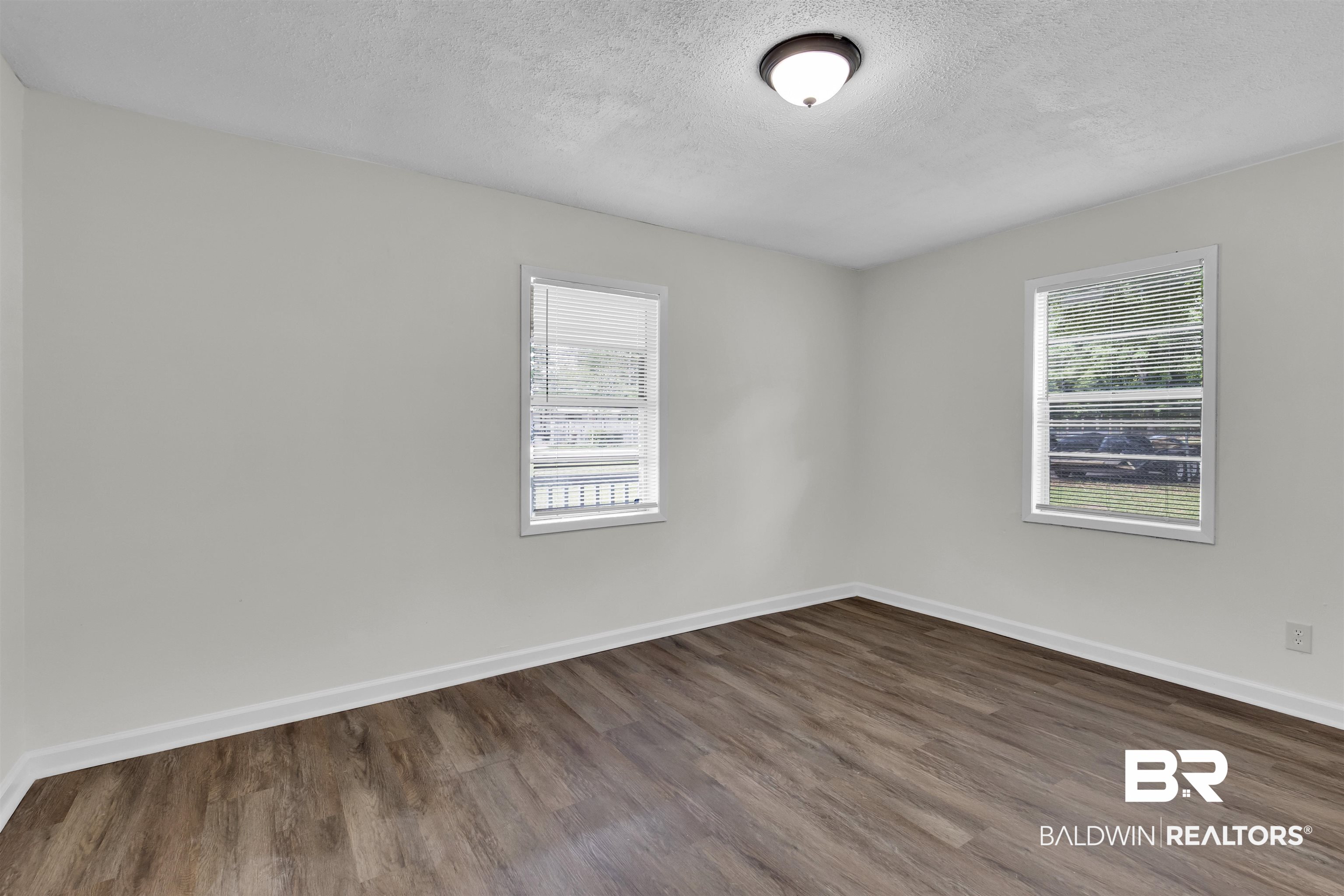 9241 Vallaris Street North Mobile, AL 36608 - Photo 4 of 17 Unfurnished room with baseboards, dark wood-type flooring, and a textured ceiling