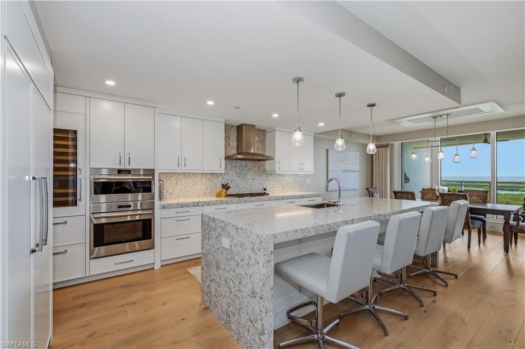 13925 Old Coast Road, Unit 905 Naples, FL 34110 - Photo 5 of 48 a large kitchen with kitchen island a dining table and chairs
