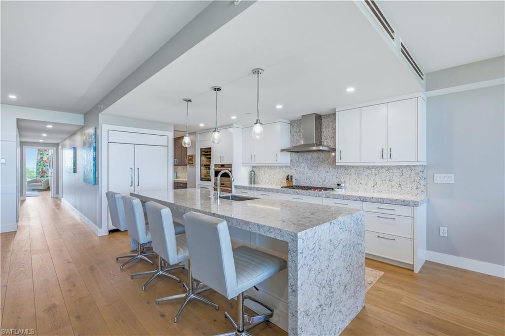 13925 Old Coast Road, Unit 905 Naples, FL 34110 - Photo 6 of 48 a large kitchen with kitchen island a dining table chairs and white cabinets