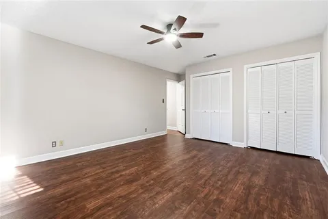 an empty room with wooden floor and ceiling fan