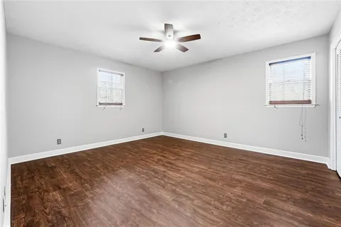 an empty room with wooden floor and ceiling fan