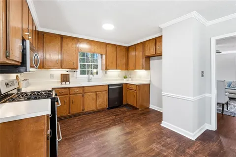 a kitchen with a sink appliances cabinets and a large window