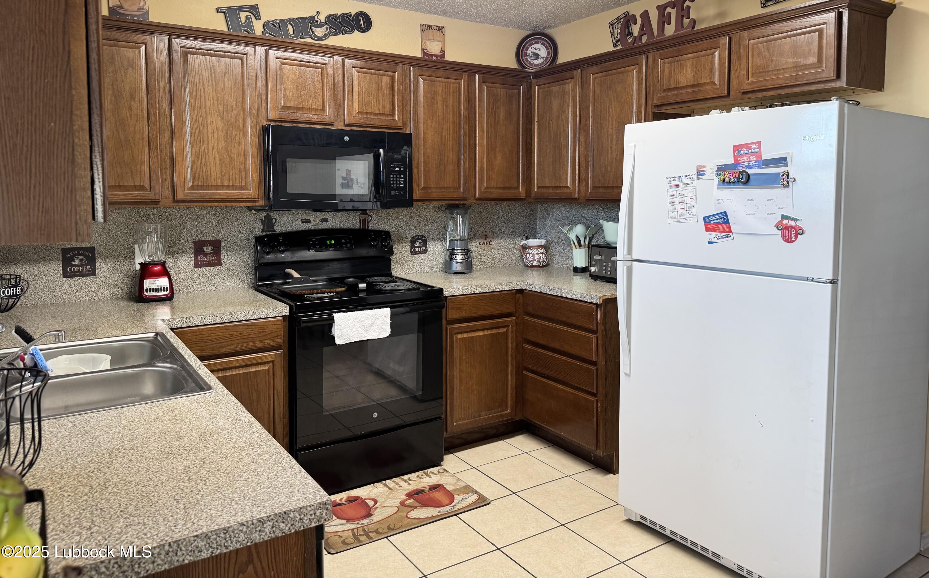 303 77th Street Lubbock, TX 79404 - Photo 3 of 9 a kitchen with stainless steel appliances granite countertop a refrigerator sink stove and microwave