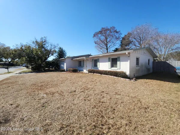 a front view of house with yard and trees in the background