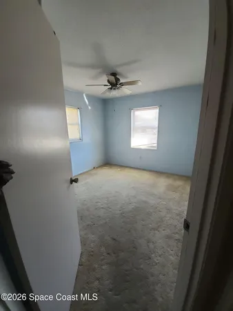 en empty room with windows and ceiling fan