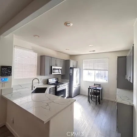 a kitchen with stainless steel appliances granite countertop a sink a stove a dining table and chairs with wooden floor