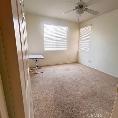 an empty room with windows and fan