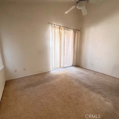 an empty room with a window and a ceiling fan
