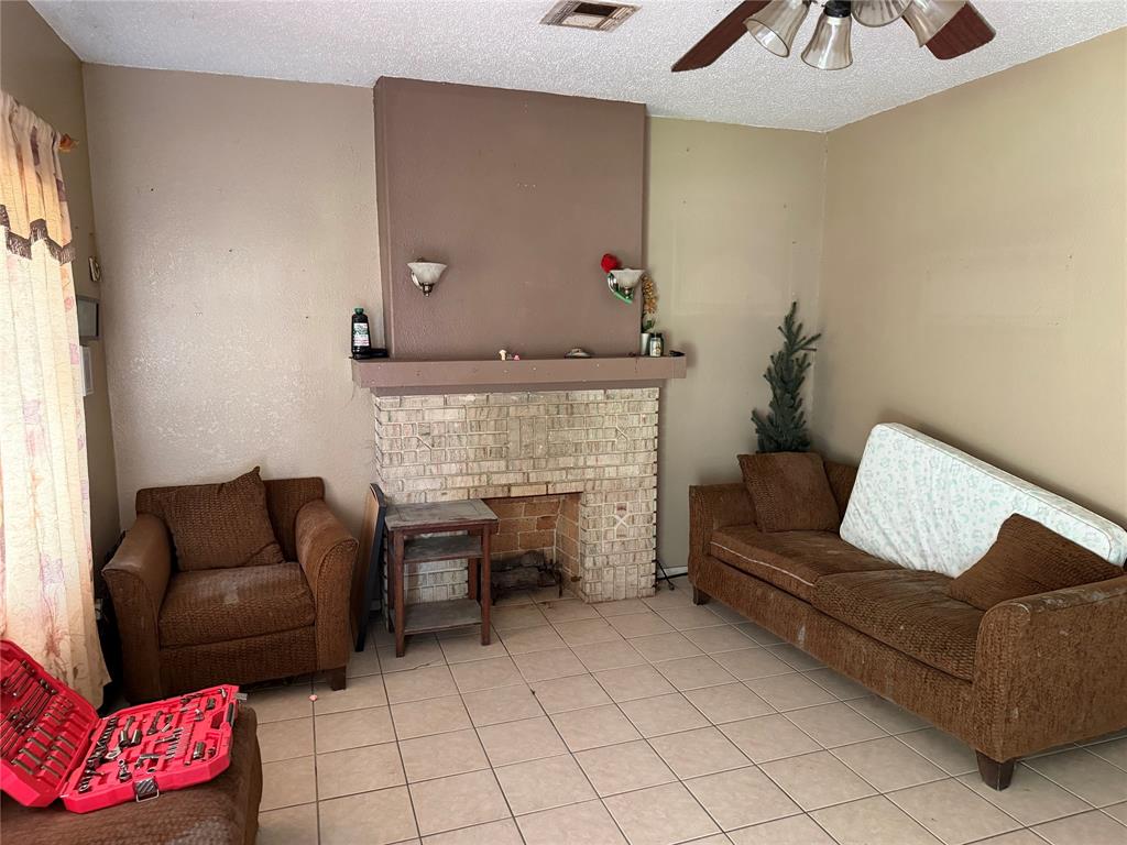 1530 Proctor Avenue Waco, TX 76708 - Photo 2 of 6 Living area featuring a brick fireplace with a mantle, tile flooring, and a ceiling fan with integrated lighting