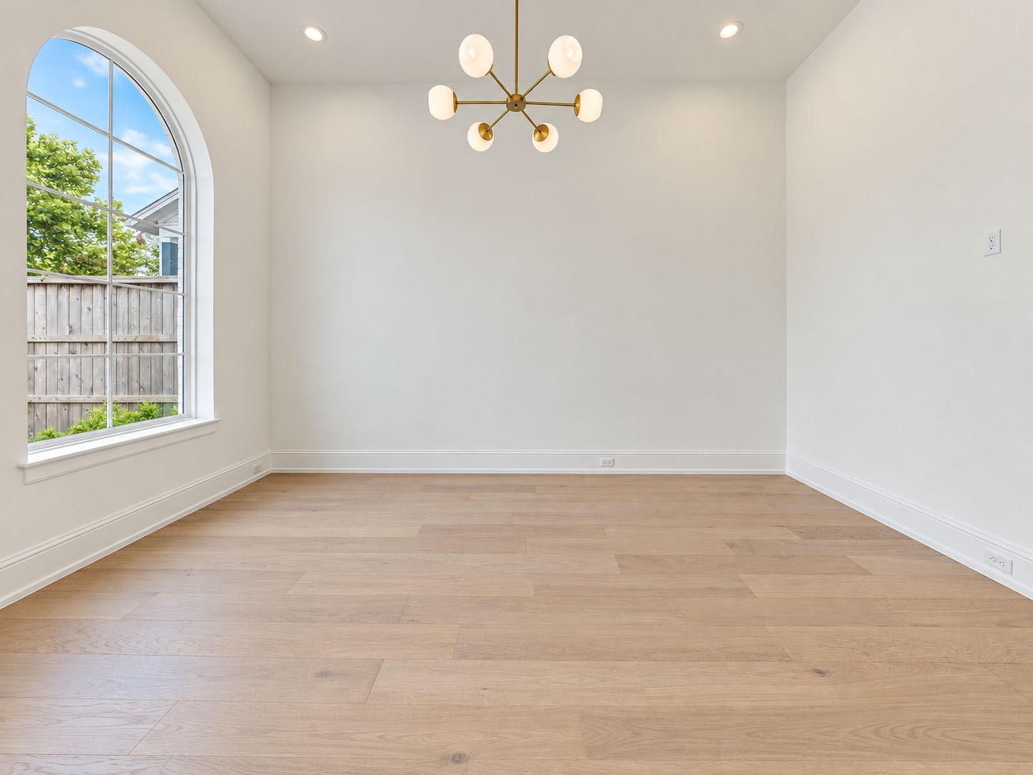 2309 Hollister Road Houston, TX 77080 - Photo 6 of 47 Elegant dining room pairs clean contemporary design with warm wide-plank flooring and a sculptural statement chandelier. A graceful arched window fills the space with natural light and leafy views, creating a sophisticated setting for intimate dinners, holiday celebrations, and memorable gatherings.