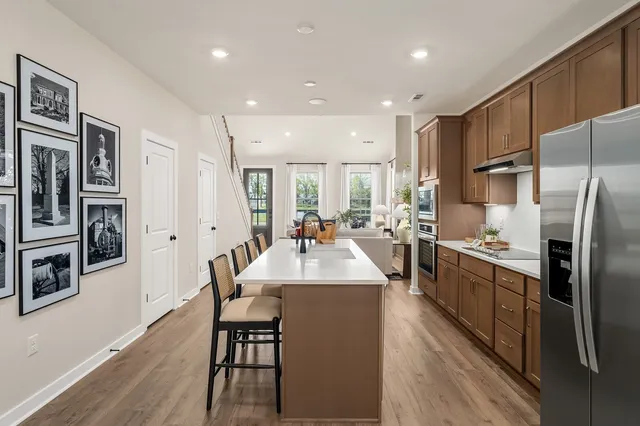 a large kitchen with stainless steel appliances kitchen island granite countertop a large refrigerator a sink a stove and white cabinets with wooden floor