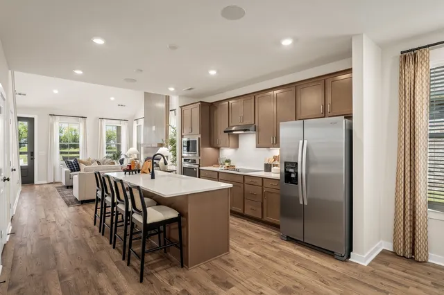 a kitchen with stainless steel appliances granite countertop a refrigerator a stove a sink a dining table and chairs