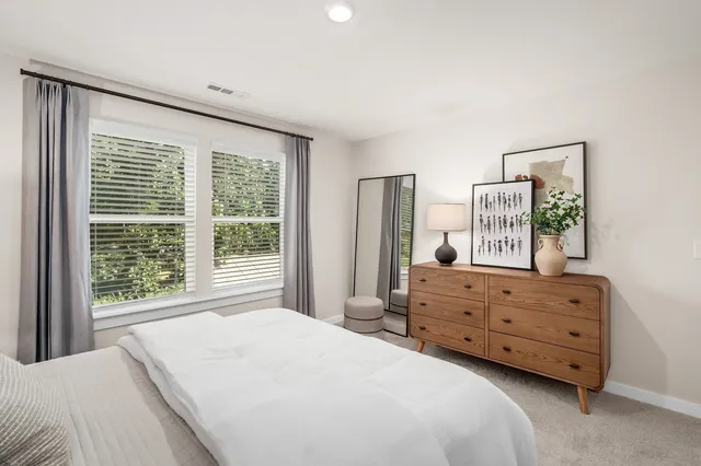 a bedroom with a bed a window and dresser