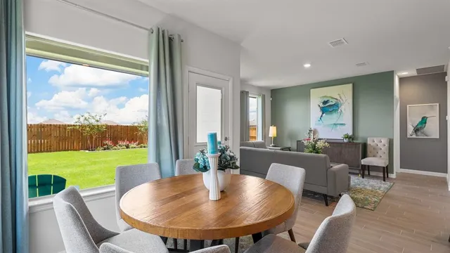 a kitchen with stainless steel appliances granite countertop a dining table chairs refrigerator and cabinets