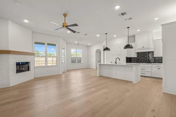 a view of kitchen with granite countertop kitchen island wooden floors stainless steel appliances and a fireplace