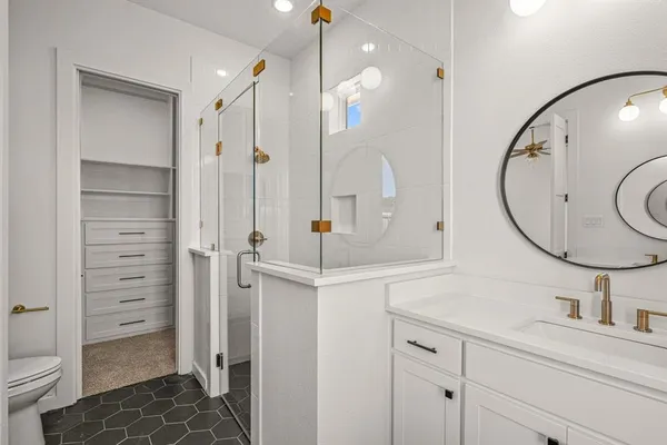 a bathroom with a sink a toilet a mirror and shower