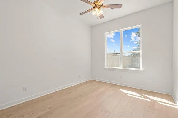 an empty room with a window and a fan