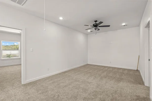 an empty room with a ceiling fan and carpet