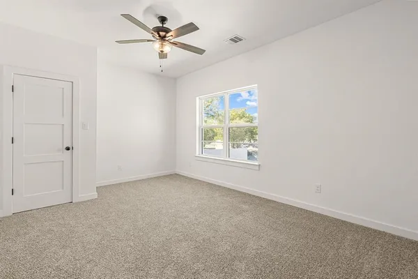 an empty room with windows and fan